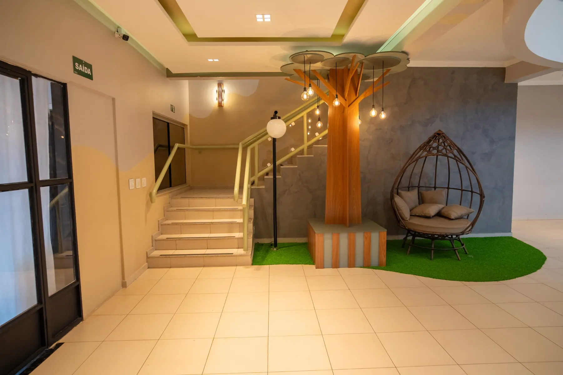 Hall de entrada com árvore decorativa e escada para o mezanino